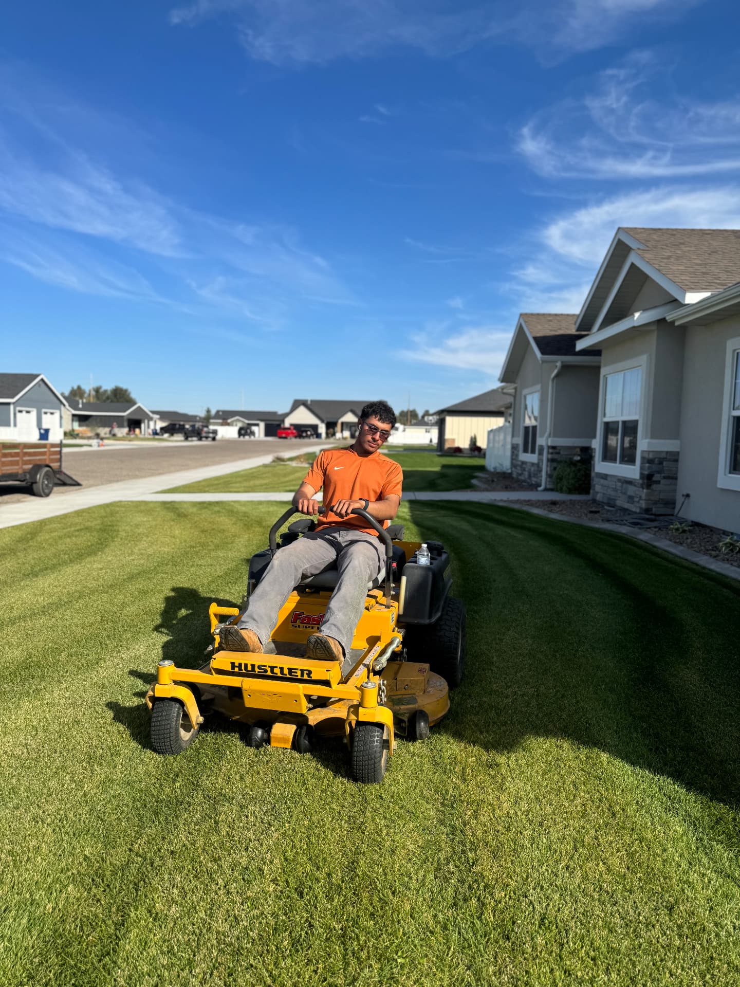 Ricardo riding a zero-turn mower across a freshly striped lawn in Burley, Idaho — R & R Lawncare and Construction
