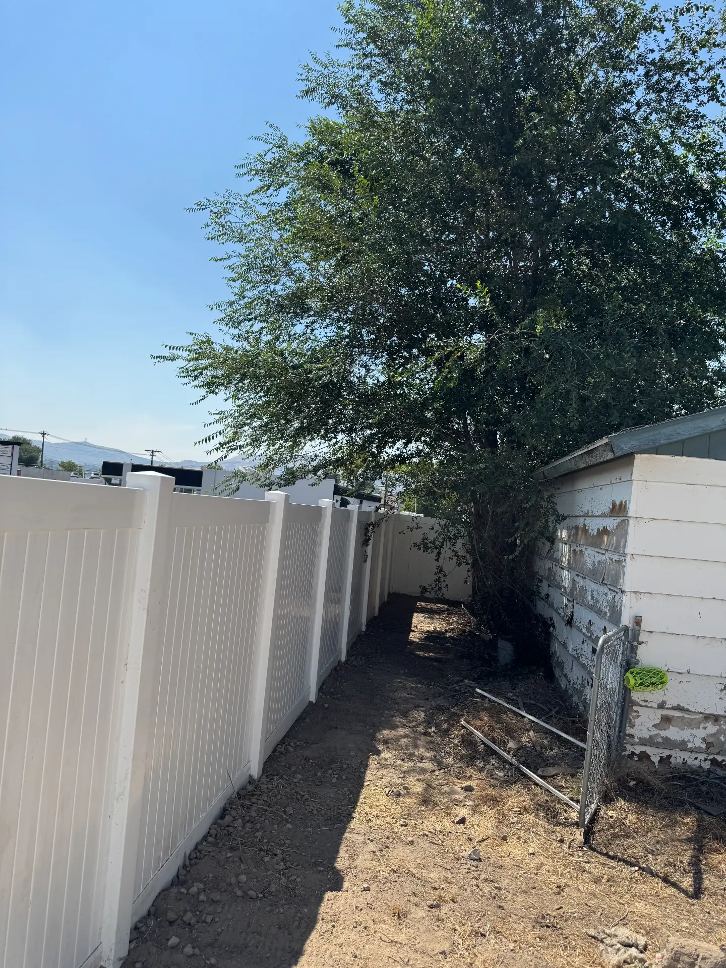 White vinyl privacy fence running along a side yard — R & R Construction, Burley Idaho