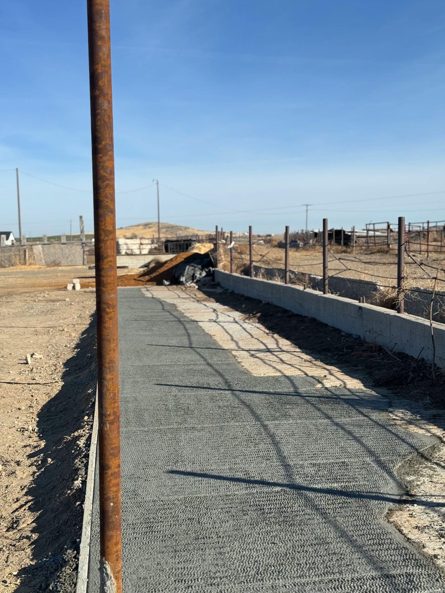 Fresh concrete path along a new fence line on a rural property — R & R Construction, Burley Idaho
