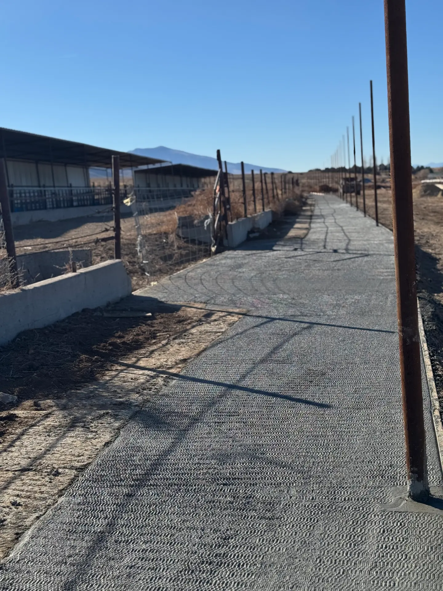 Broom-finished concrete walkway with new fence posts set — R & R Construction, Burley Idaho