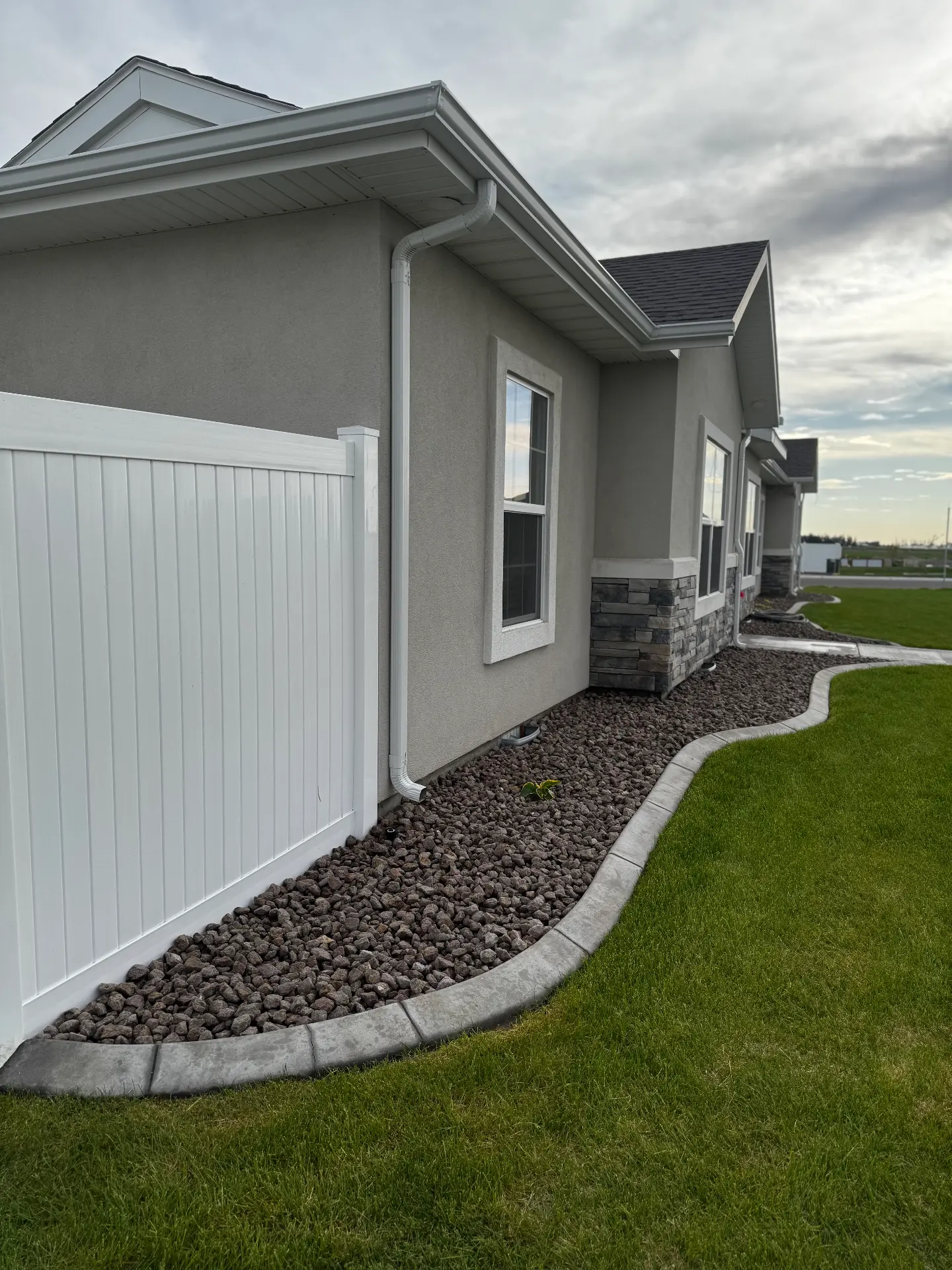 White vinyl privacy fence line with clean landscaping — R & R Construction, Burley Idaho