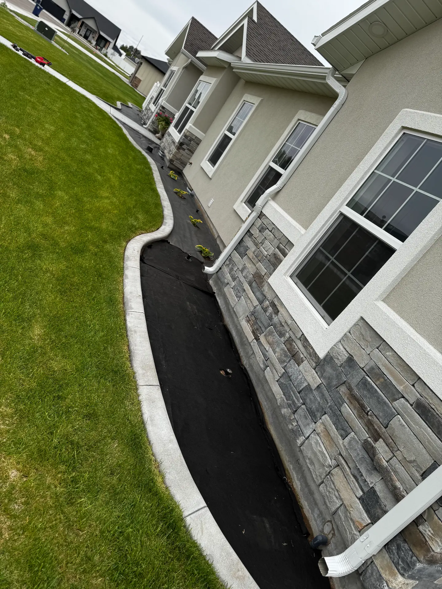 Concrete curbing along a stone accent wall and landscape bed — R & R Construction, Burley Idaho